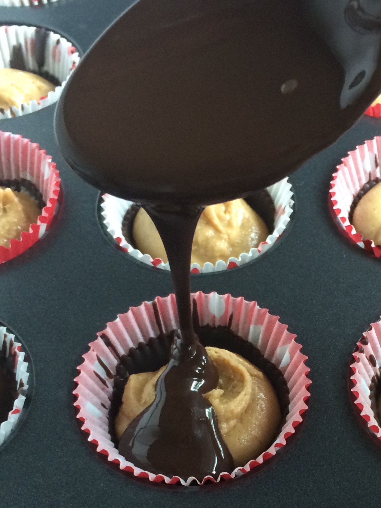 drizzling chocolate over peanut butter with a spoon