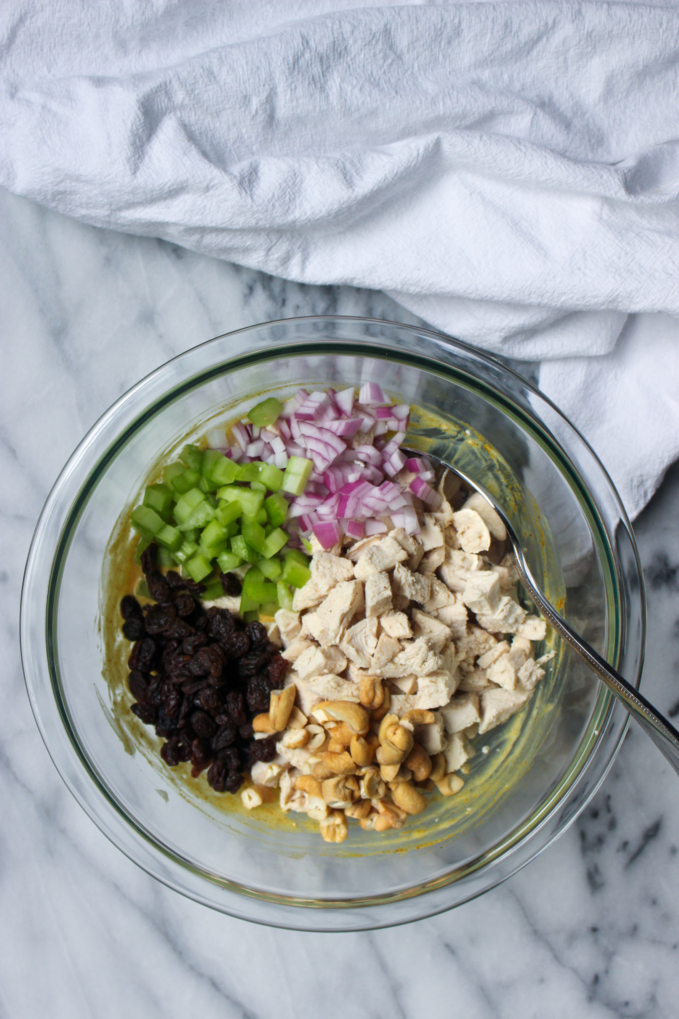 cooked chicken, cashews, raisins, celery, and red onion in a bowl for chicken salad