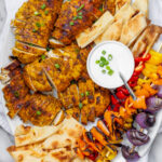 big platter of grilled chicken, veggie skewers, na'an, and garlic sauce
